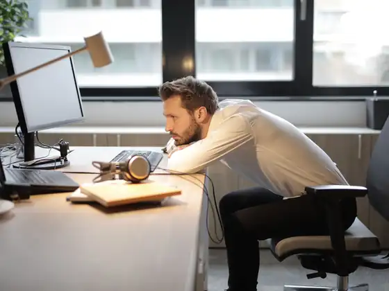 Homme affalé sur son bureau illustrant la perte de sens au travail